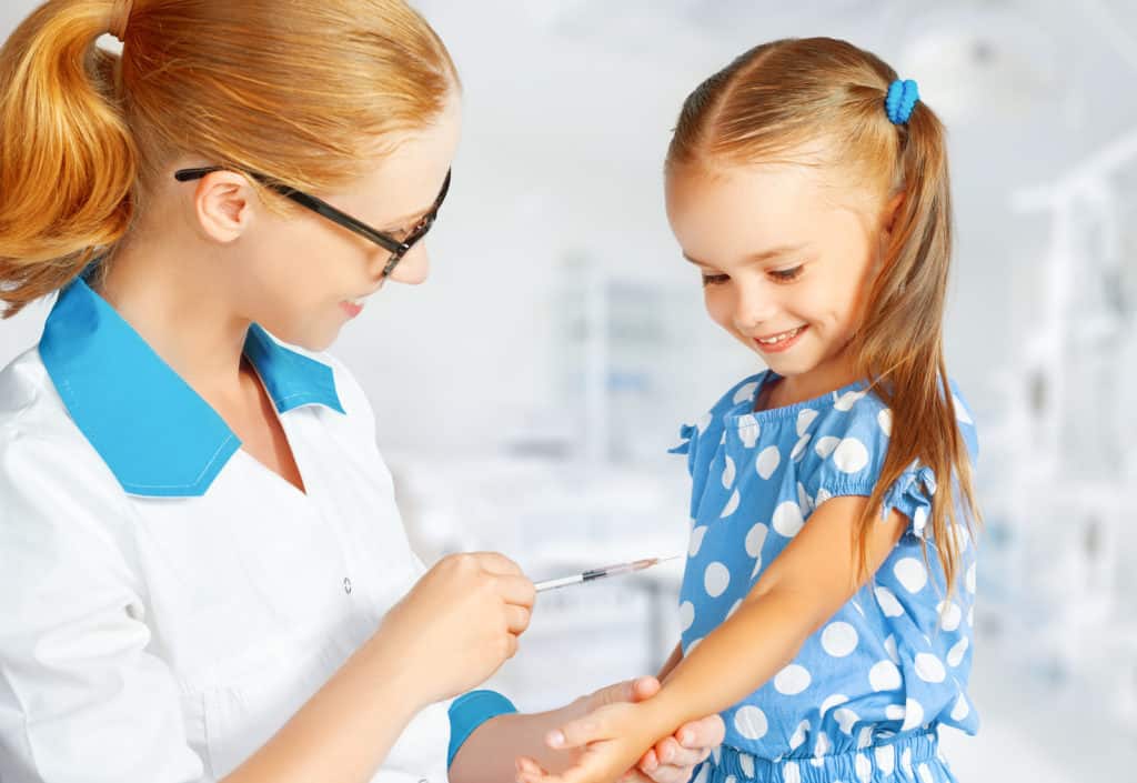 Pediatrician vaccinating little girl