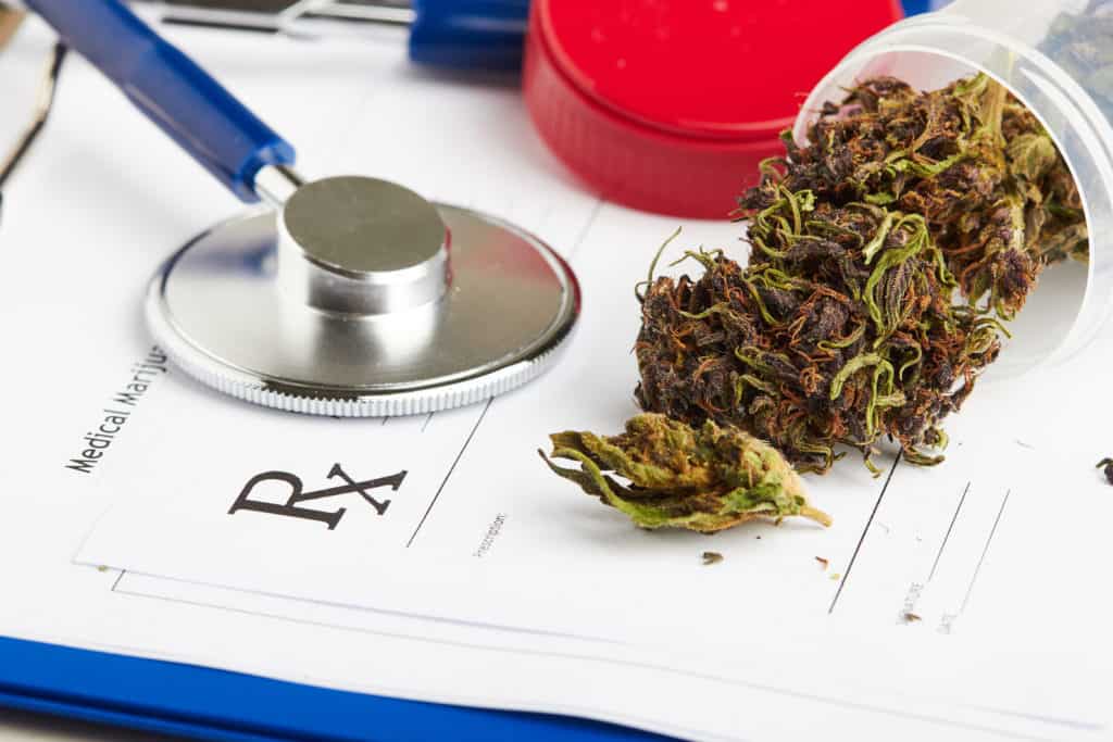 Medical marijuana in jar lying on prescription form near stethoscope.