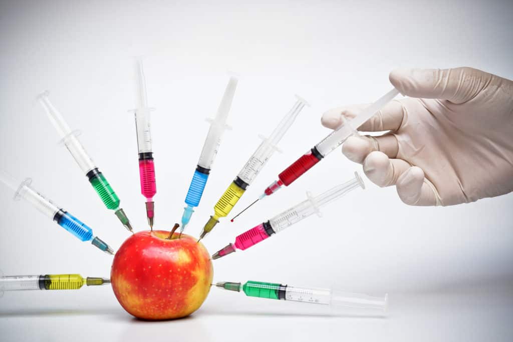 Injection into red apple - Genetically modified fruit and syringe with colorful chemical GMO food