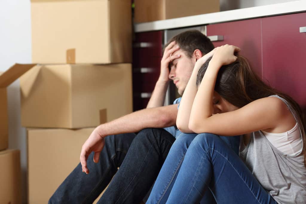 Angry evicted couple worried moving house sitting on the floor in the kitchen