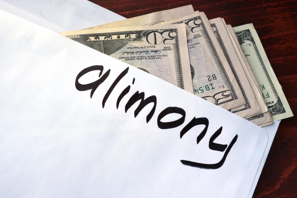 Alimony written on an envelope with dollars.