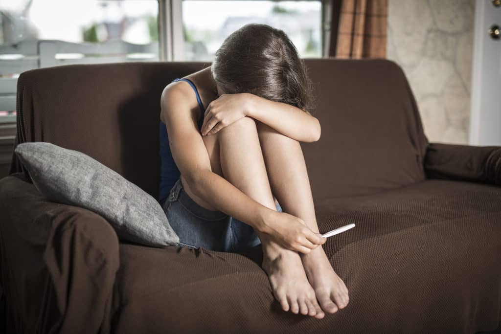 unhappy woman with pregnancy test