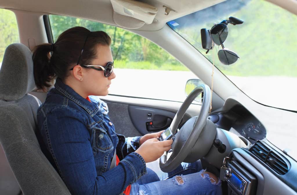 Teen drives car while distracted by text messaging on cell phone