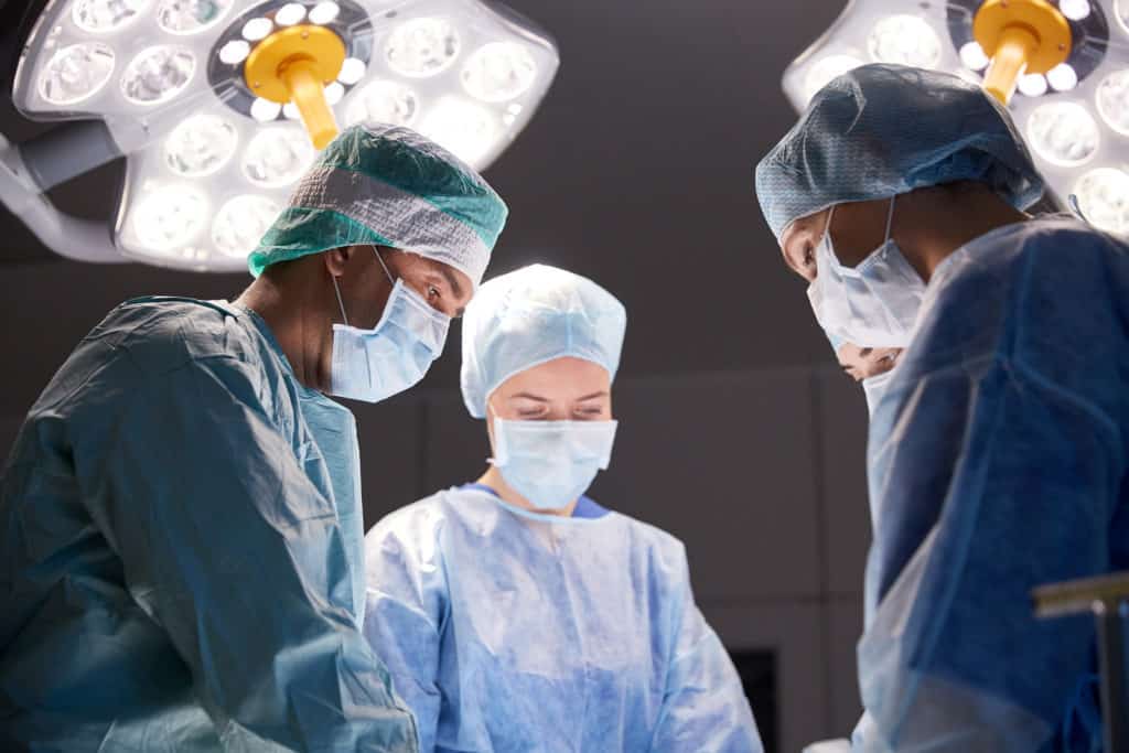 surgery, medicine and people concept - group of surgeons at operation in operating room at hospital