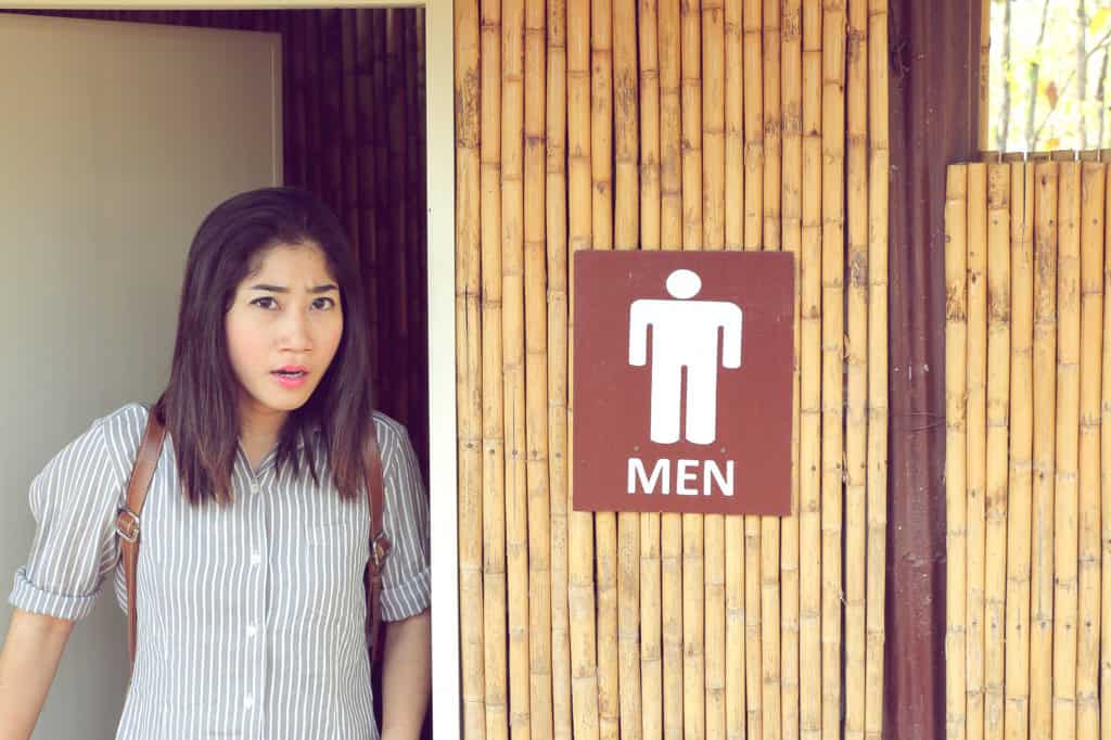 transgender woman leave from the men's toilet looking straight and upset.