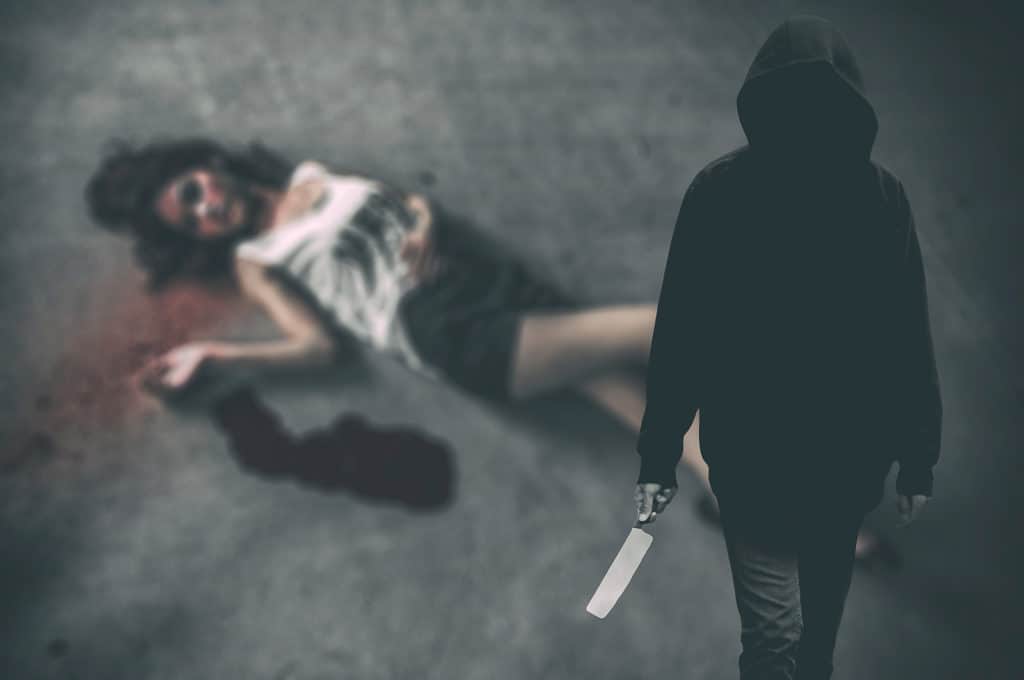 Murderer hooded man ready to attack to kill his victim that is the woman to died on ground. (Criminal concept)