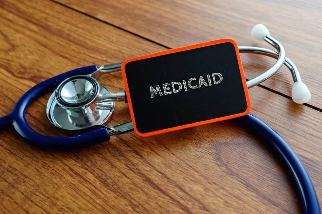 Medical concept.Word MEDICAID with stethoscope on wooden table.