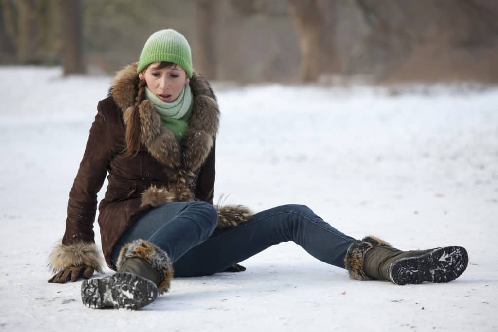 woman slips and falls down on snowy road