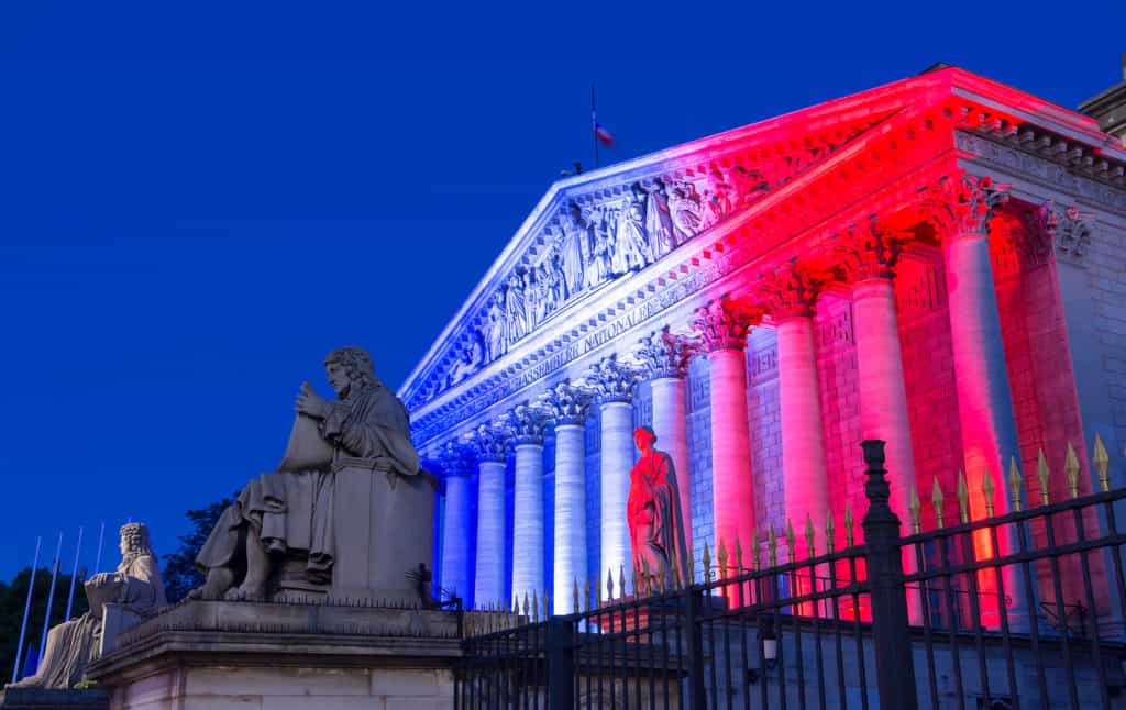 The French National Assembly lit up with colors of French national flag at night, Paris, France.