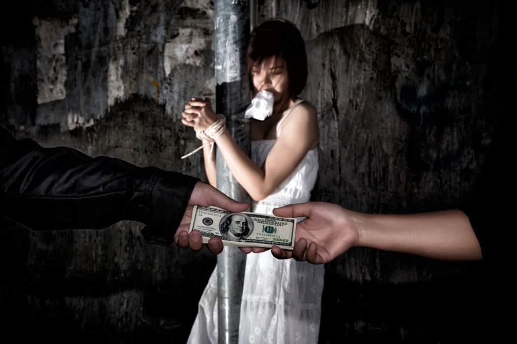 Human trafficking concept. Person hand with a dollar banknote buying victim woman in pain and bound hands with rope. missing kidnapped. in dark tone.