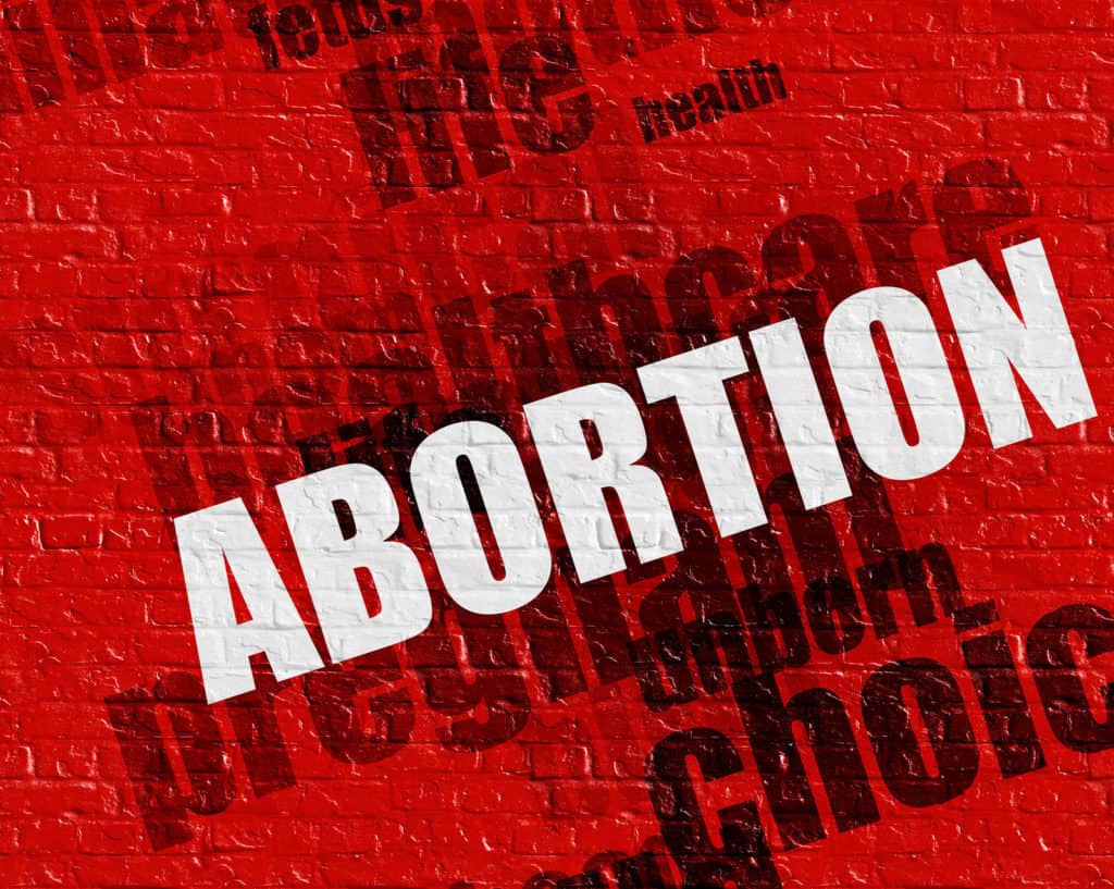 Modern medical concept: Abortion - on the Brickwall with Word Cloud Around . Red Brick Wall with Abortion on the it .