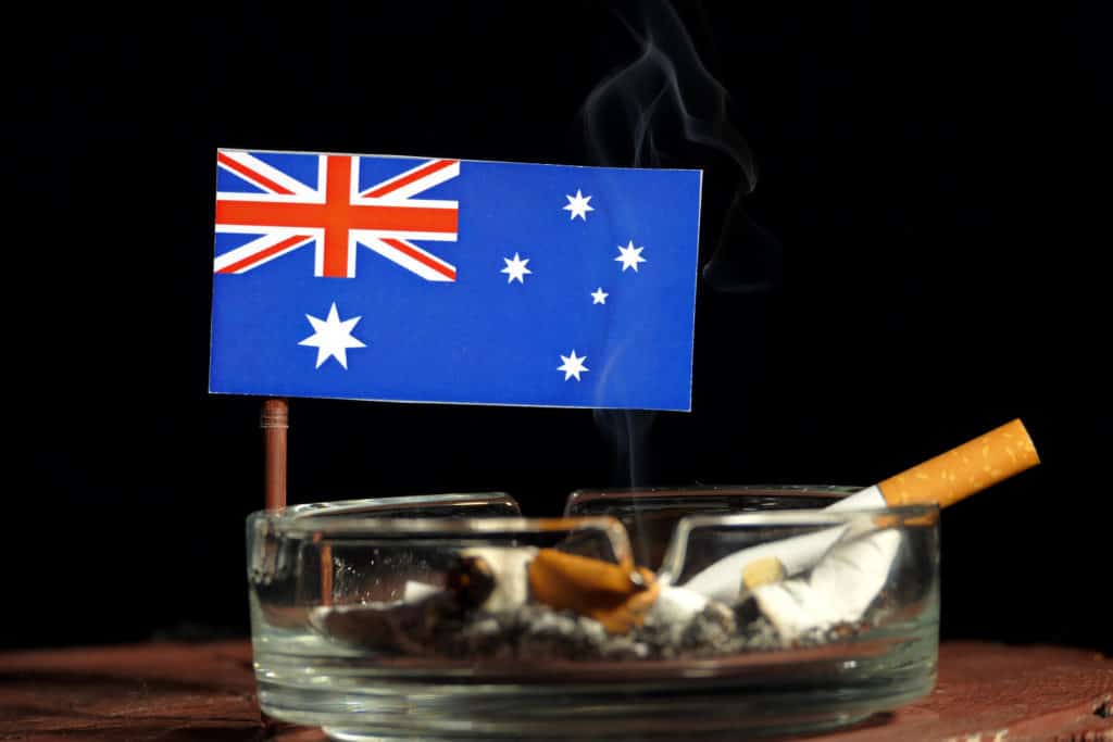 Australian flag with burning cigarette in ashtray isolated on black background