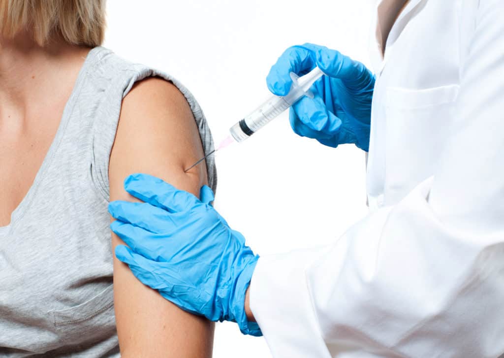 Vaccination. Doctor injecting flu vaccine to patient's arm. Doctor making woman an injection