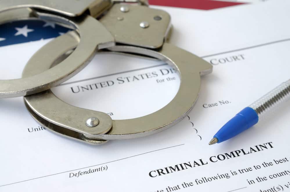 District Court Criminal complaint court papers with handcuffs and blue pen