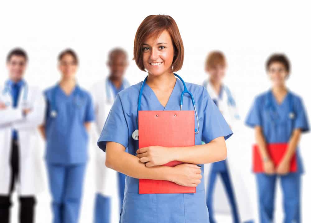 Portrait of a smiling nurse in front of a group of medical workers