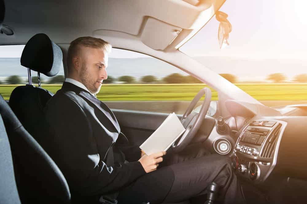 man reading book while car is self driving