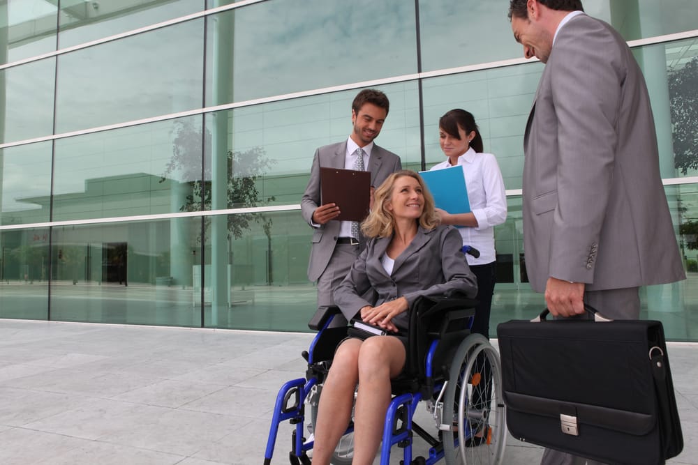 photo of woman in wheelchair with lawyer in front of courthouse