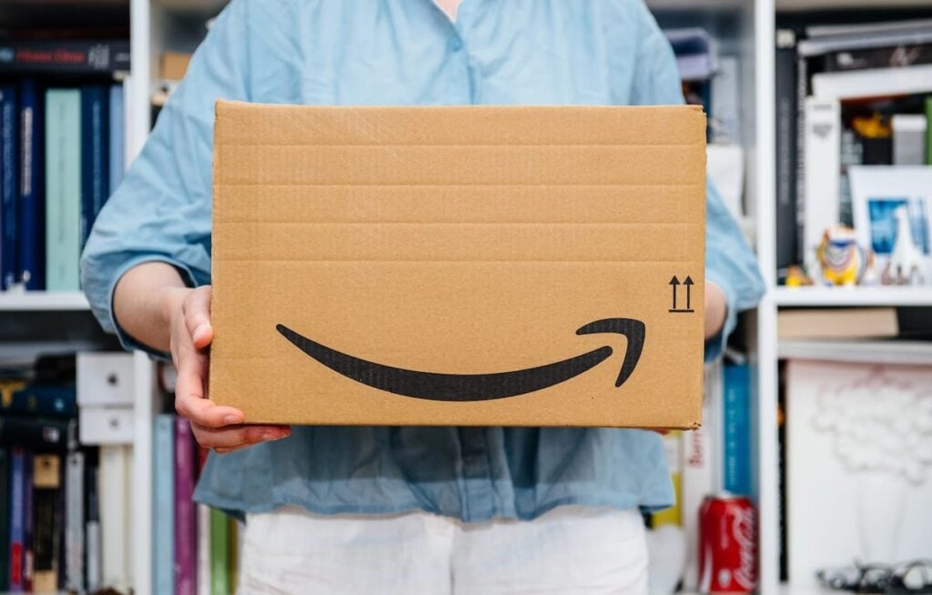 Person holding a cardboard Amazon package, symbolizing online purchases that may be subject to product recalls.