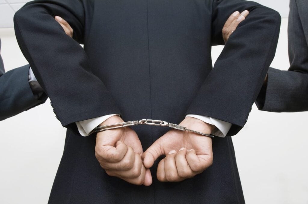 corporate executive in handcuffs and being taken away
