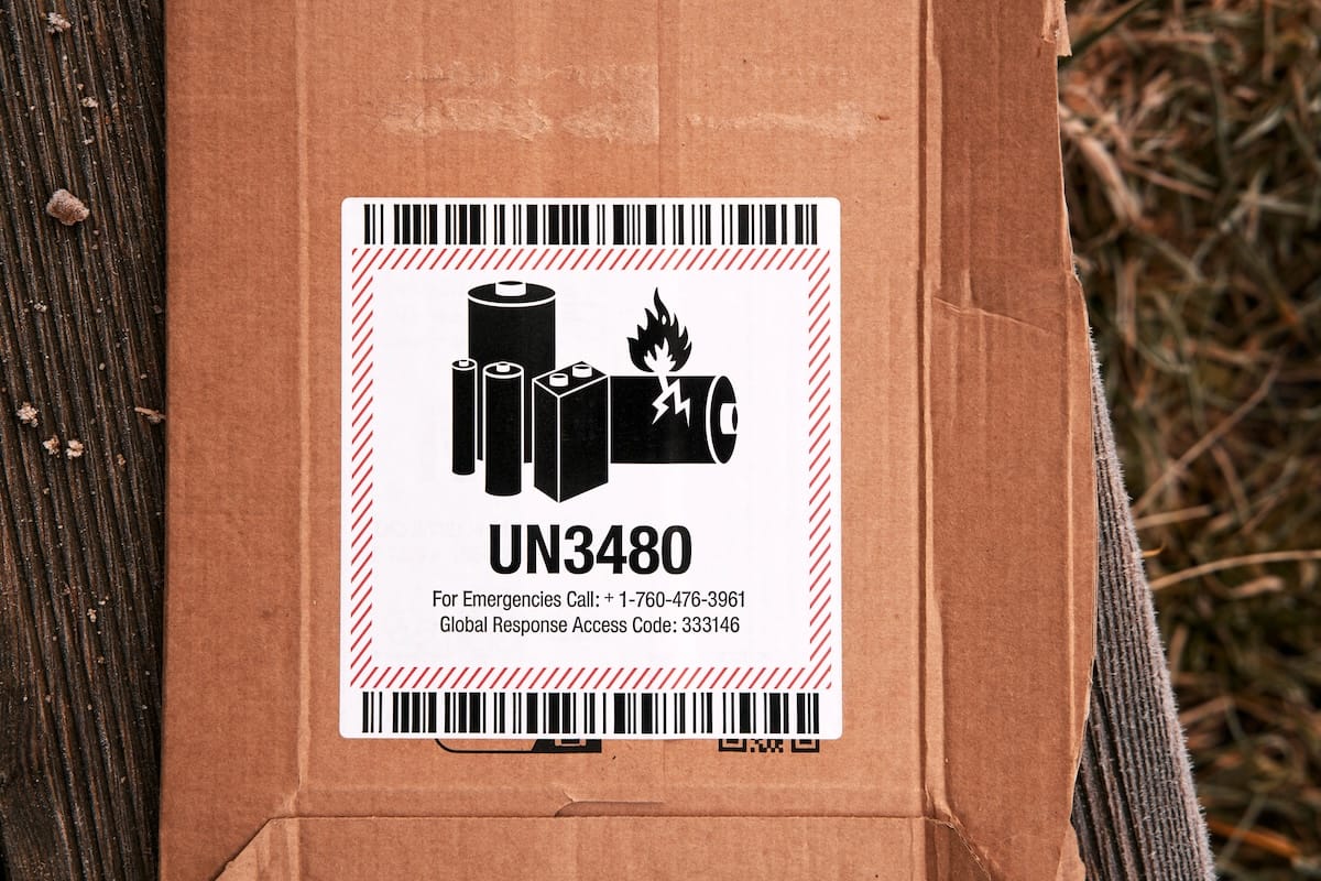 Box with a UN3480 lithium battery hazard label warning of fire risk, an example of regulated product shipping safety.