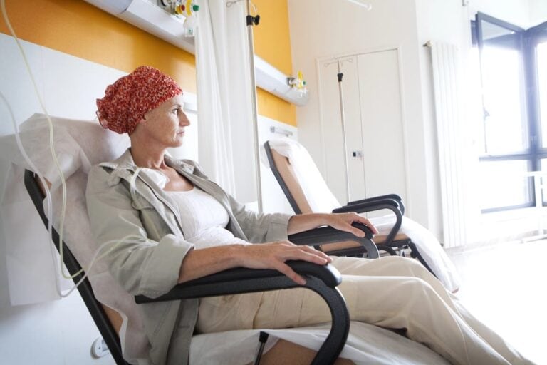 Woman in a headscarf sitting in a hospital infusion chair during cancer treatment
