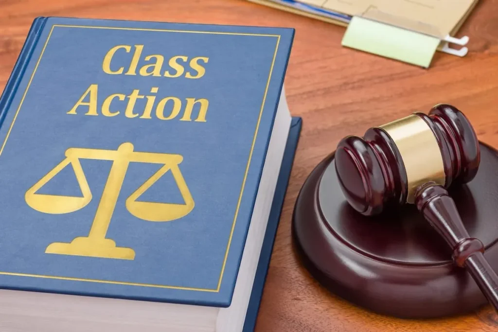 Blue law book titled Class Action beside a wooden gavel