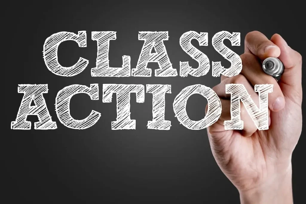 Hand writing Class Action in chalk-style letters on a dark background