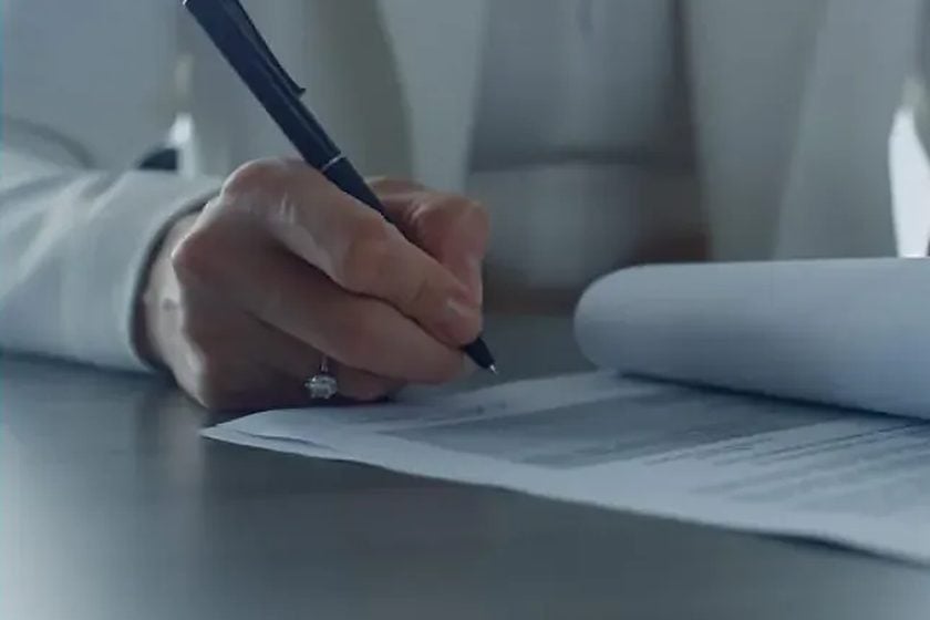 Close-up of a hand signing a legal document with a pen