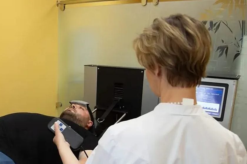 Man lying on an exam table while a clinician runs a medical test