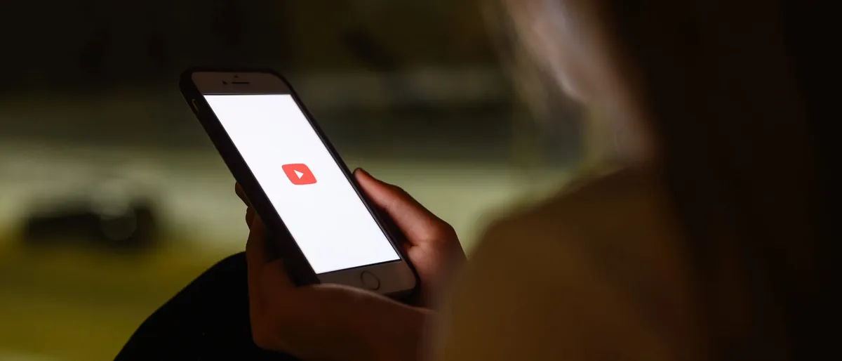 Teenager holding a smartphone with the YouTube app open at night
